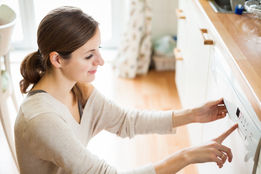 Housework: young woman putting dishes in the dishwasher