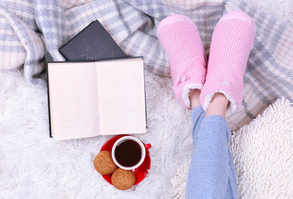 Composition with warm plaid, book, cup of hot drink and female