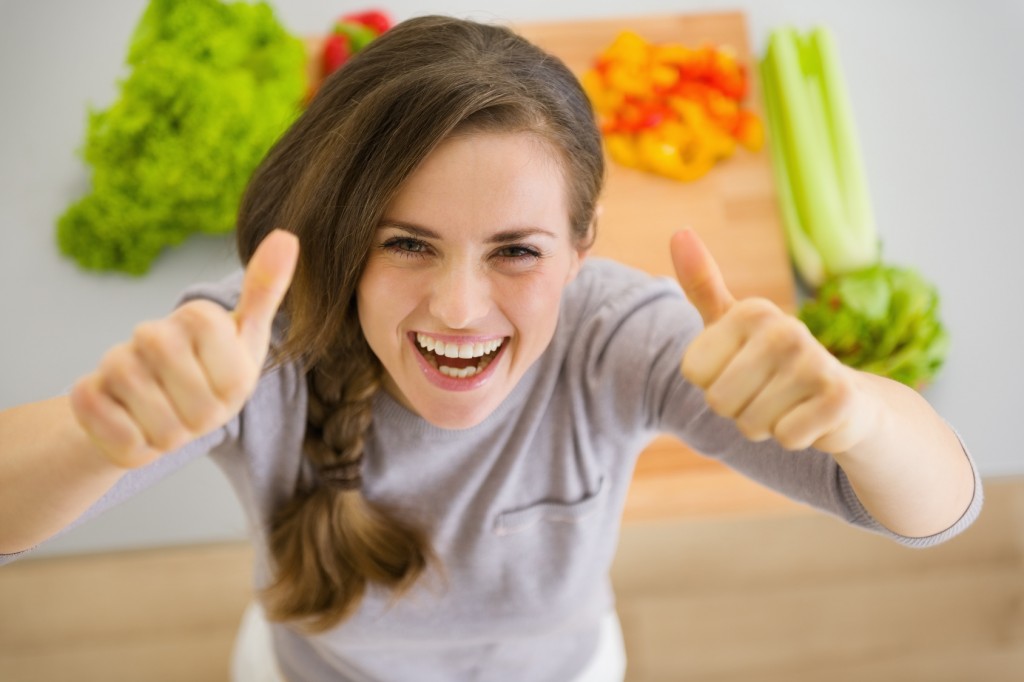 Happy young housewife in modern kitchen showing thumbs up