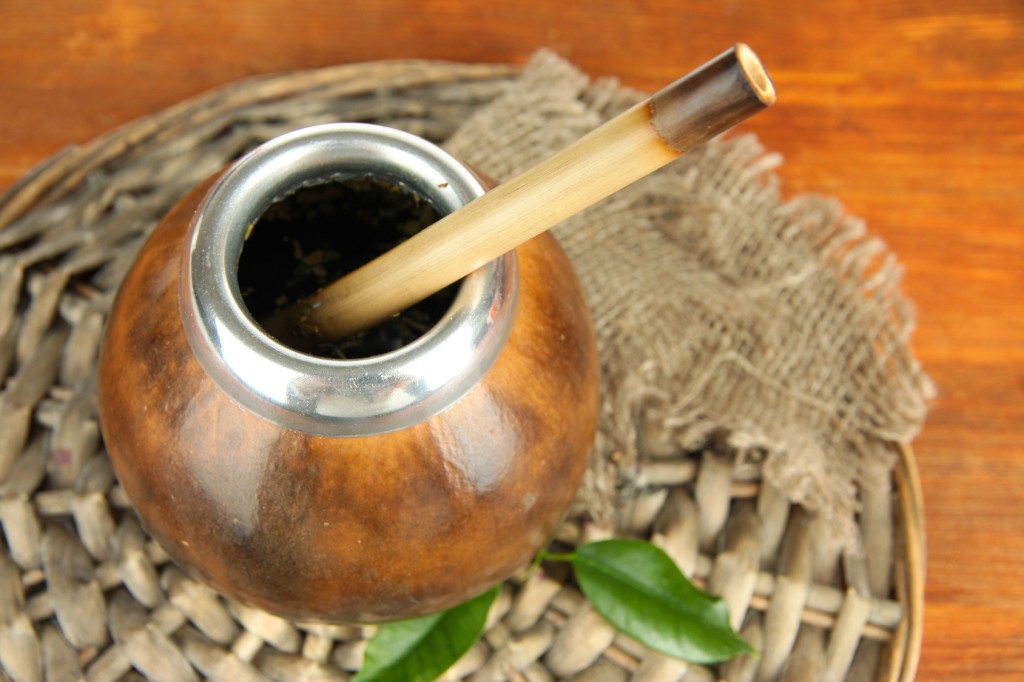 Calabash and bombilla with yerba mate on wooden background