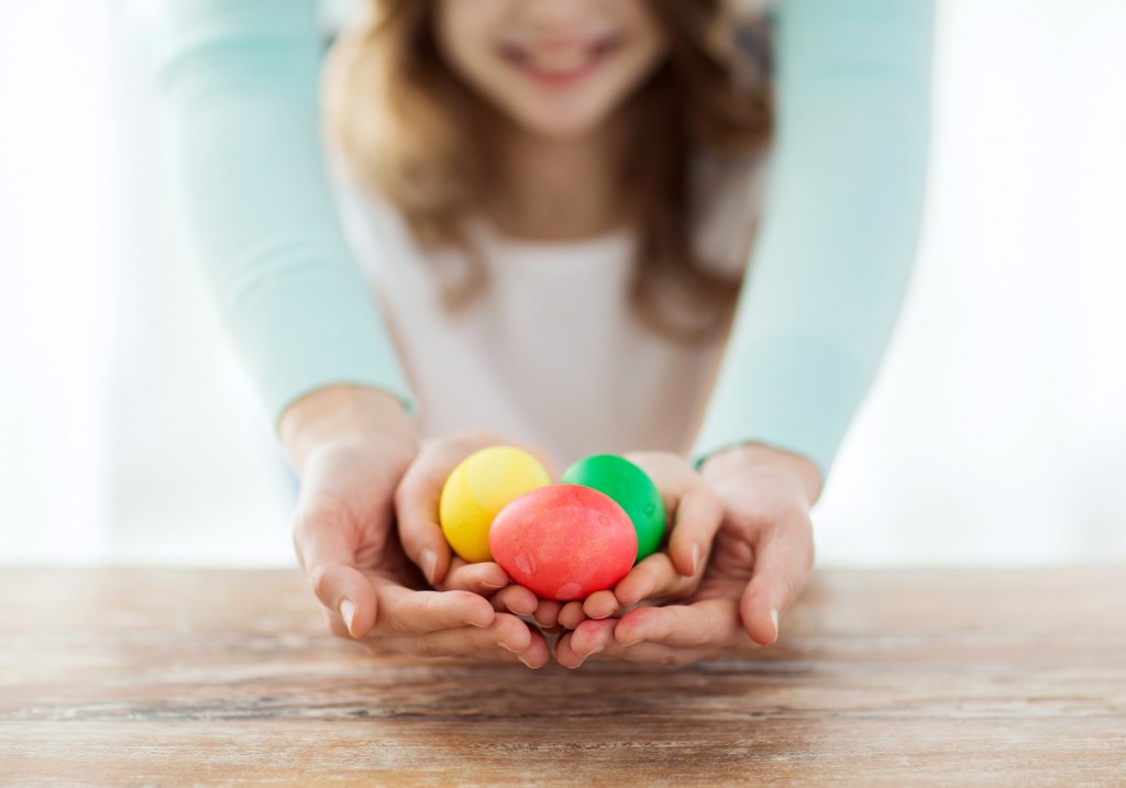 close up of girl and mother holding colored eggs