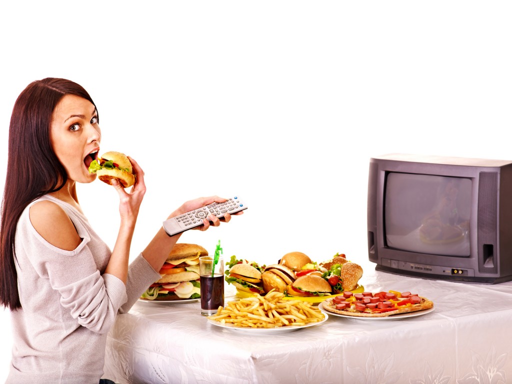 Woman eating fast food and watching TV.