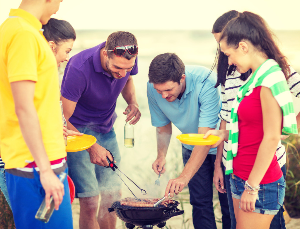 group of friends having picnic on the beach