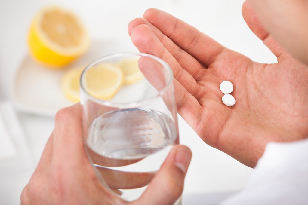 Sick Man Taking Tablets With Glass Of Water