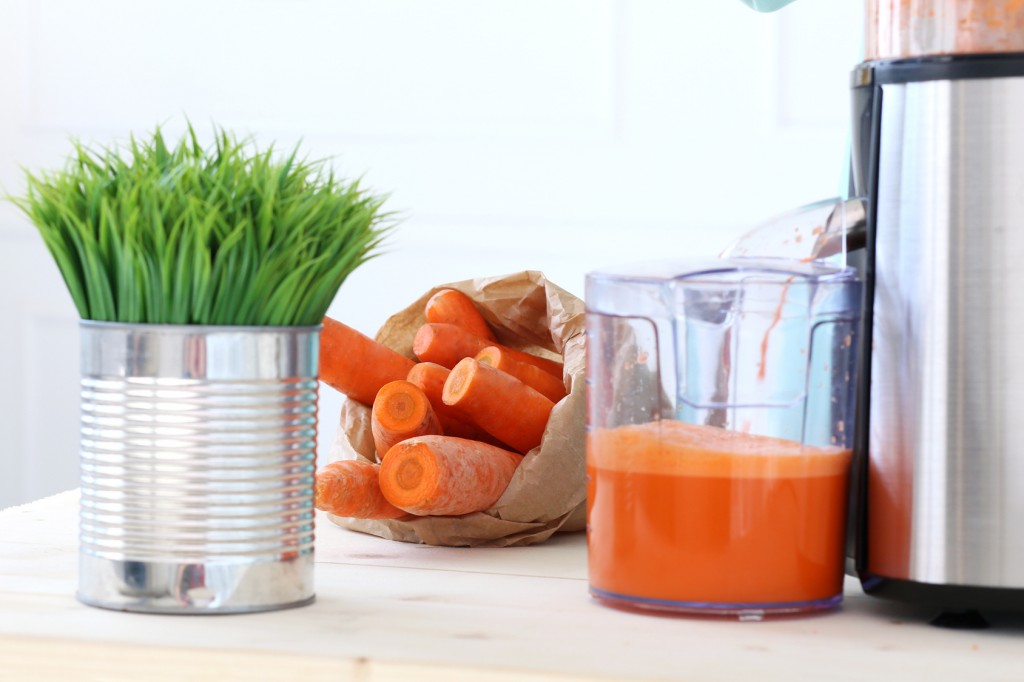 Beautiful girl making carrot juice