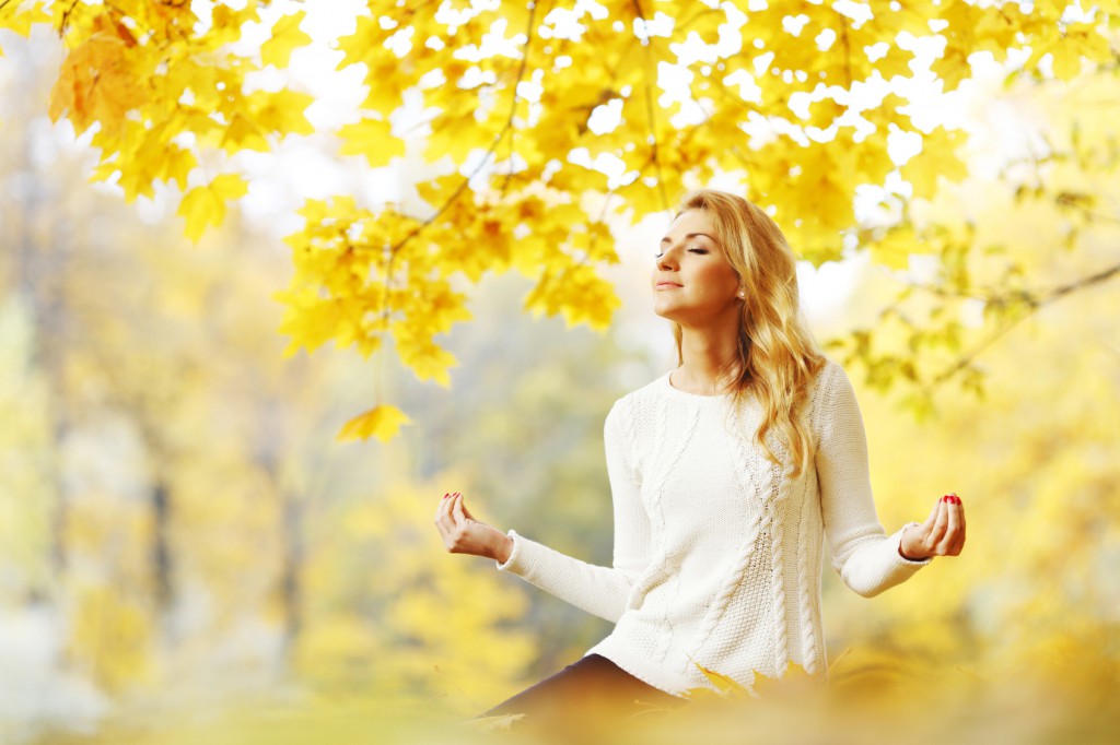Woman meditating in autumn park