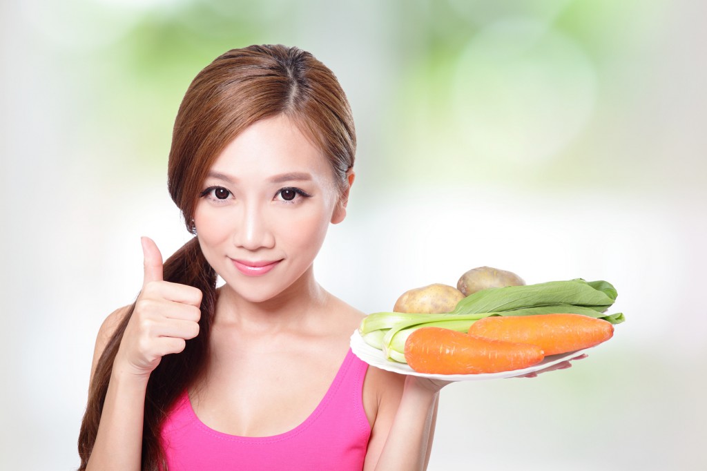 woman holding green vegetables and carrots
