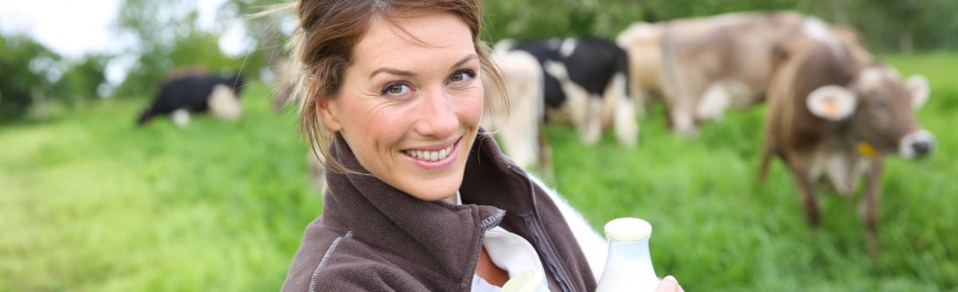 Smiling breeder woman holding bottles of milk