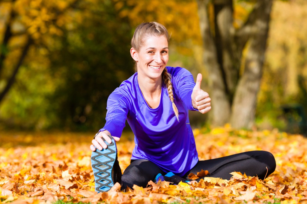 Sportswoman sport stretching in autumn leaves